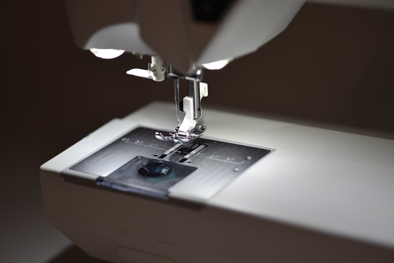 Detailed view of a sewing machines presser foot illuminated by soft lighting.