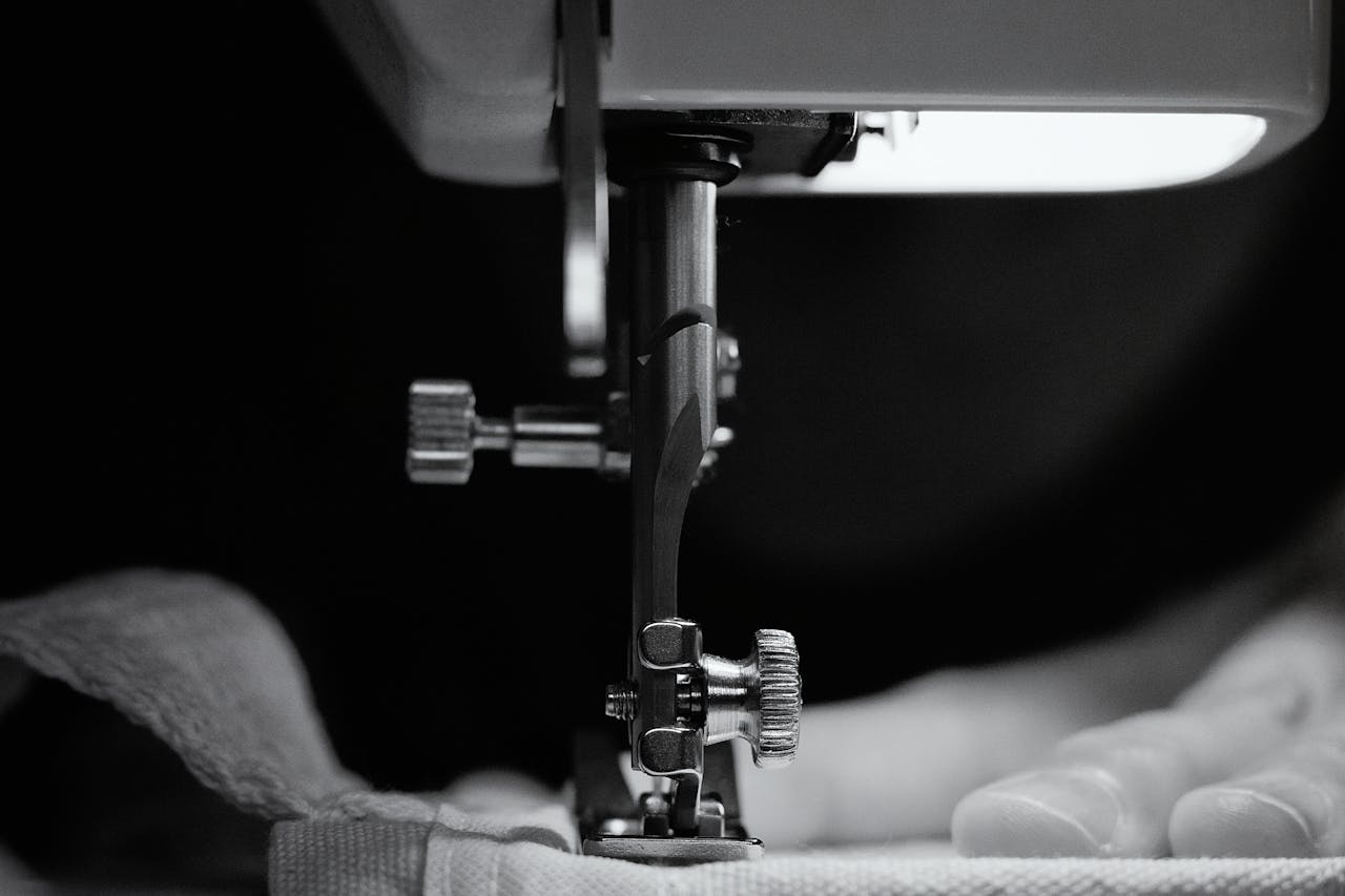 Detailed grayscale image of a sewing machine needle threading fabric, showcasing craftsmanship.